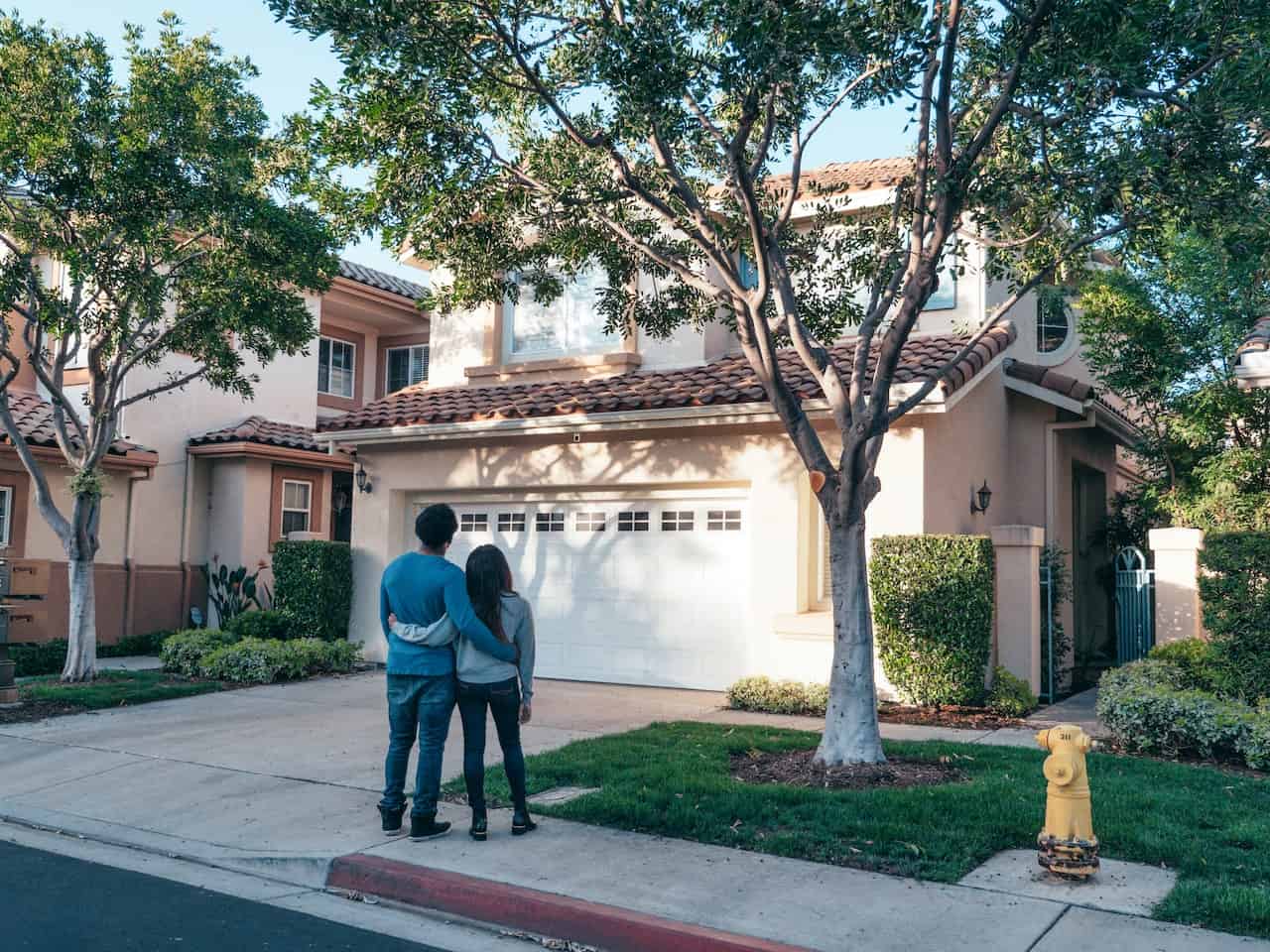 Couple in front of a stucco house on a sidewalk